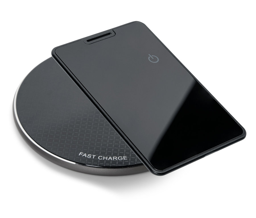Czarny smartfon leży na czarnej, okrągłej ładowarce bezprzewodowej.