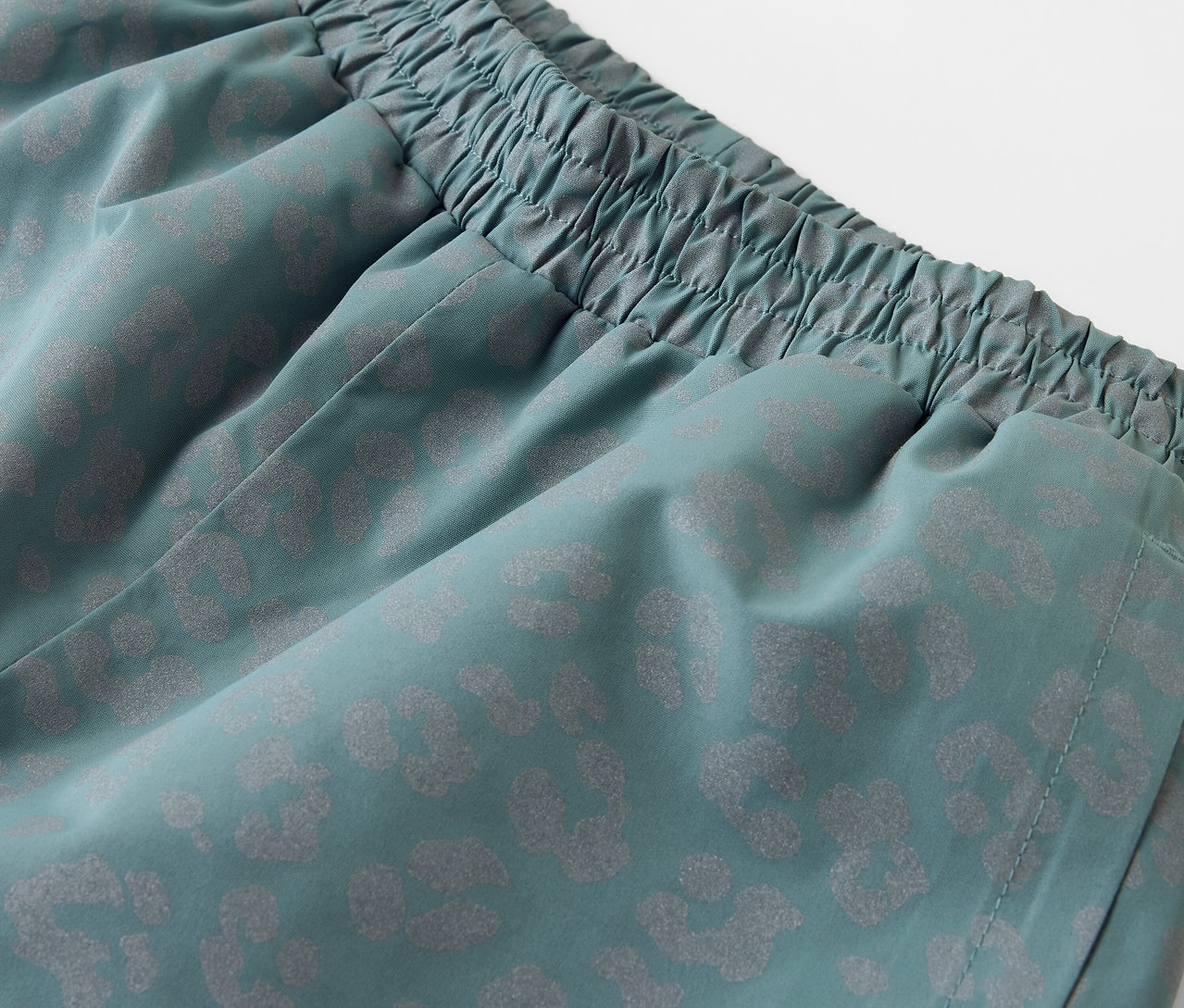 Szczegółowe ujęcie spodni przeciwdeszczowych z elementami odblaskowymi.