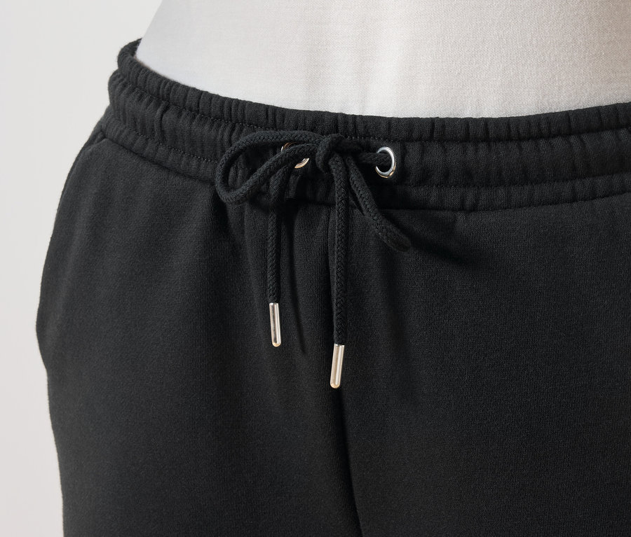 Szczegół czarnych spodni dresowych ze sznurkiem w pasie.