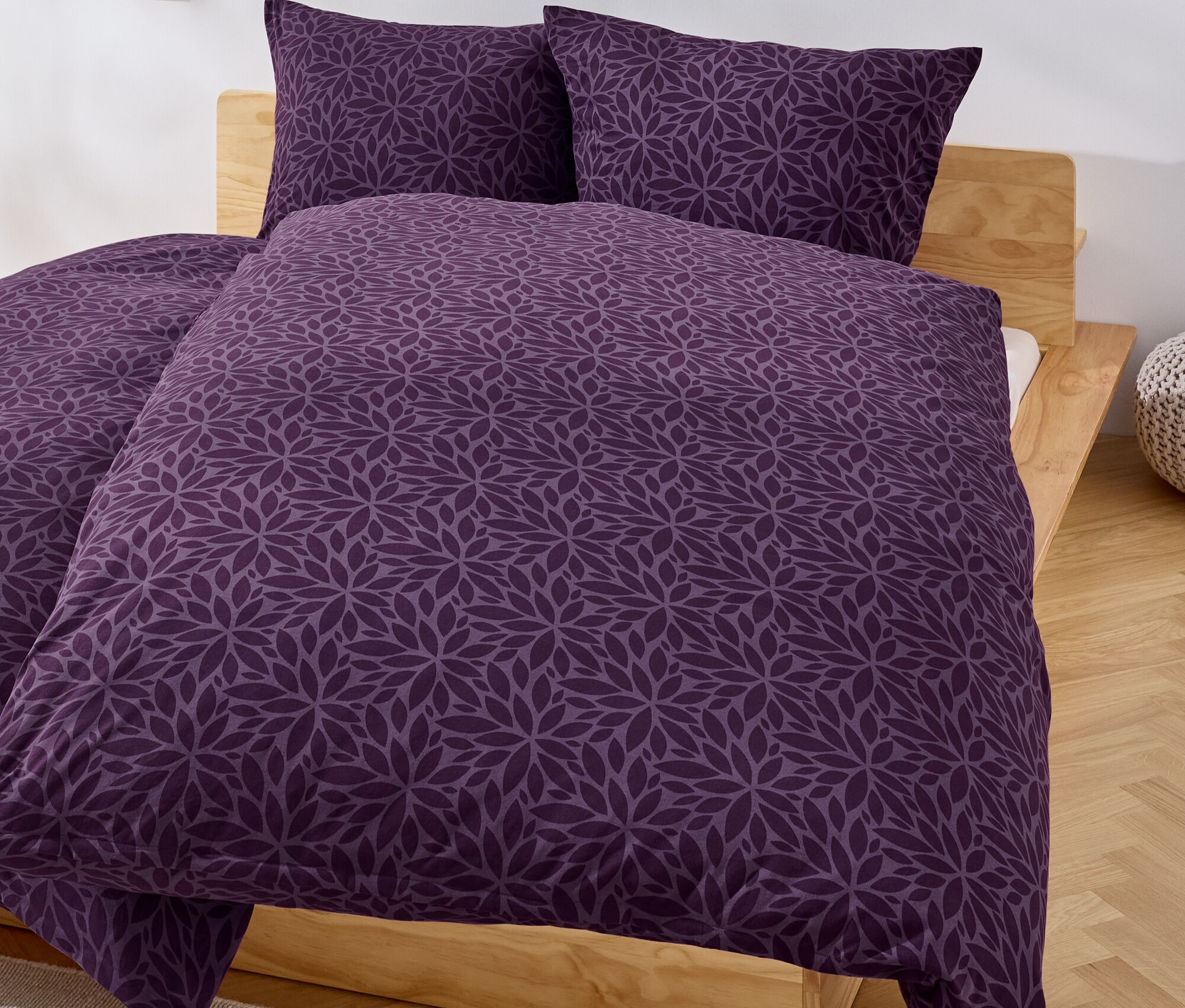 Fioletowa pościel w kwiaty na łóżku.