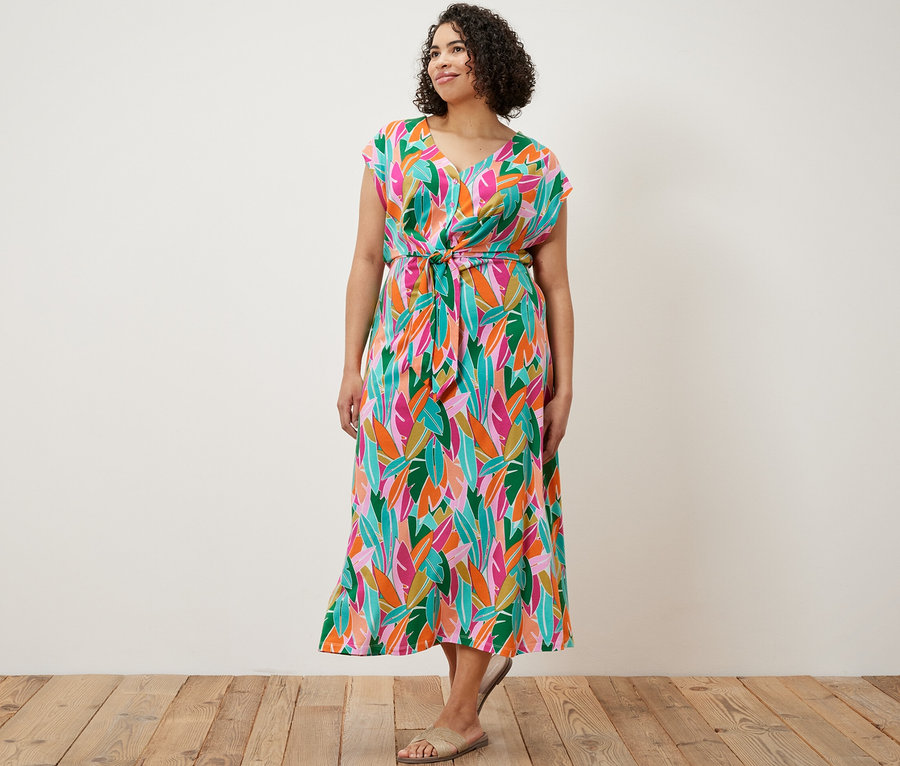 Kobieta stoi i ma na sobie sukienkę dżersejową z węzłem.