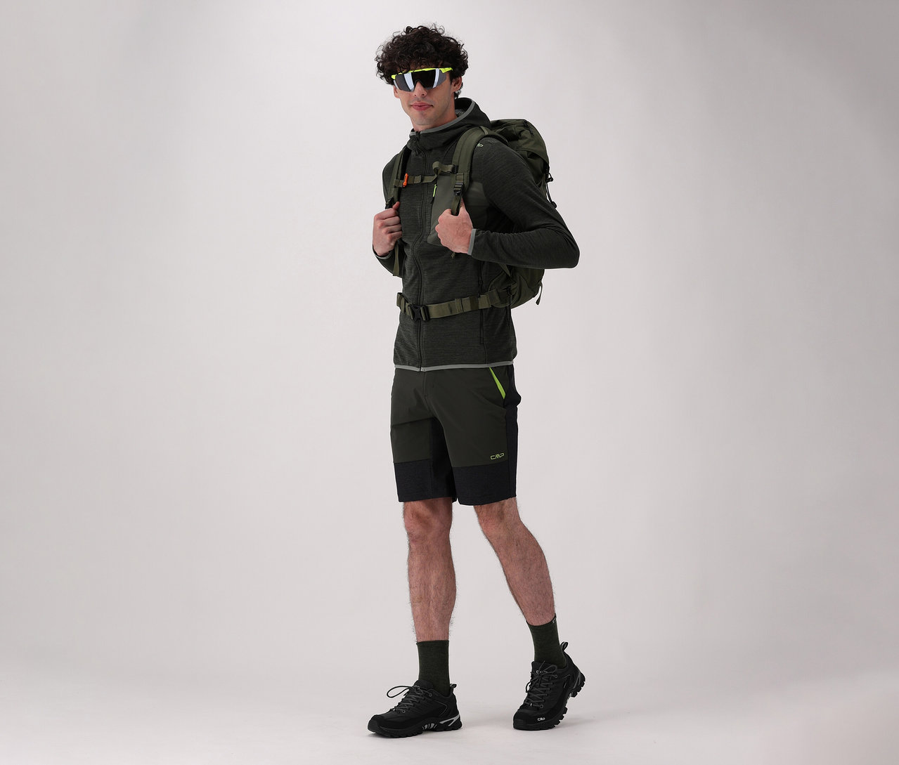 Mężczyzna z plecakiem i w butach trekkingowych CMP RIGEL LOW 2.0 WP w kolorze czarnym pozuje na jasnym tle.