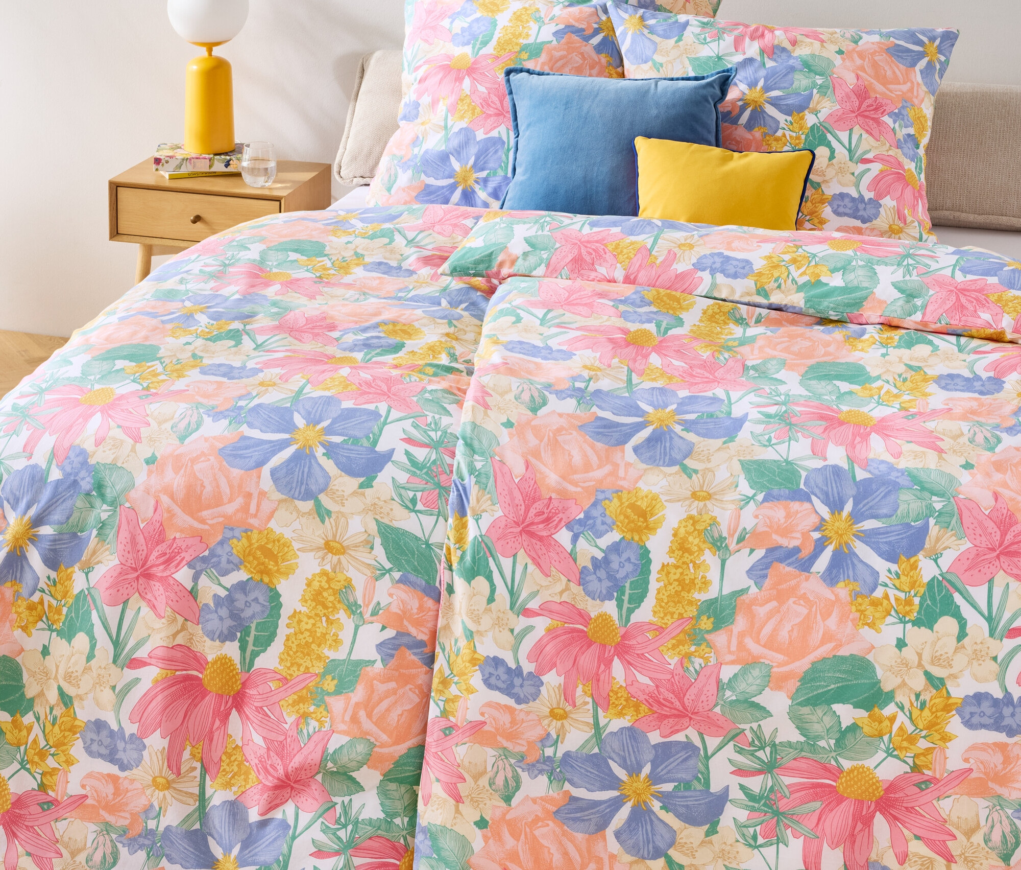 Wzorzysta pościel Renforcé w rozmiarach podwójnym, normalnym i bardzo dużym na łóżku z niebieskimi i żółtymi poduszkami.