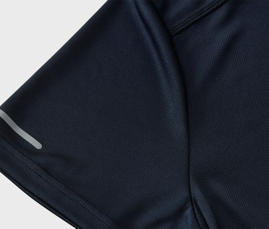 Zbliżenie granatowej koszulki sportowej z siateczkową teksturą i odblaskowym paskiem na rękawie.