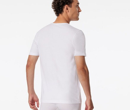 Mężczyzna tyłem, z głową odwróconą w prawo, ma na sobie biały T-shirt SCHIESSER i białe bokserki.