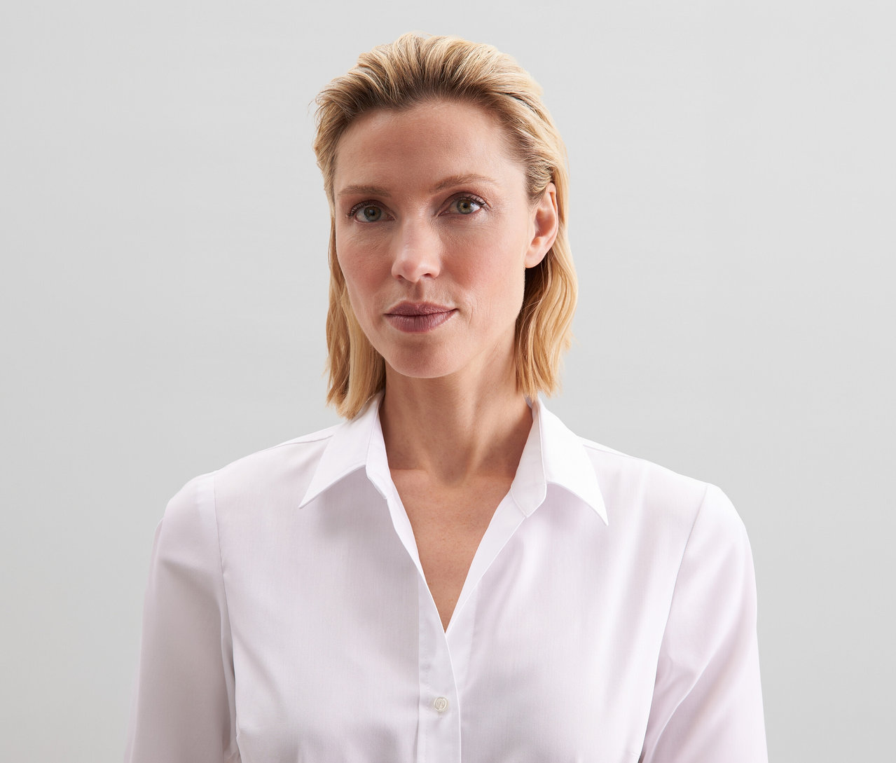 Kobieta z blond włosami nosi białą bluzkę Seidensticker Slim Fit non iron.