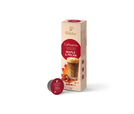 Beżowe opakowanie Cafissimo Flavoured Espresso Maple & Pecan (10 kapsułek) stoi pionowo, a przed nim leży jedna ciemnoczerwona kapsułka. Opakowanie przedstawia napój kawowy, liście klonu i orzechy pekan.