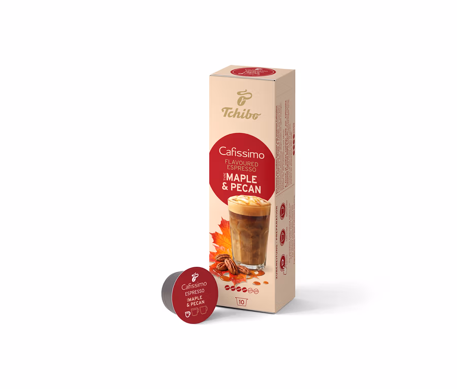 Beżowe opakowanie Cafissimo Flavoured Espresso Maple & Pecan (10 kapsułek) stoi pionowo, a przed nim leży jedna ciemnoczerwona kapsułka. Opakowanie przedstawia napój kawowy, liście klonu i orzechy pekan.