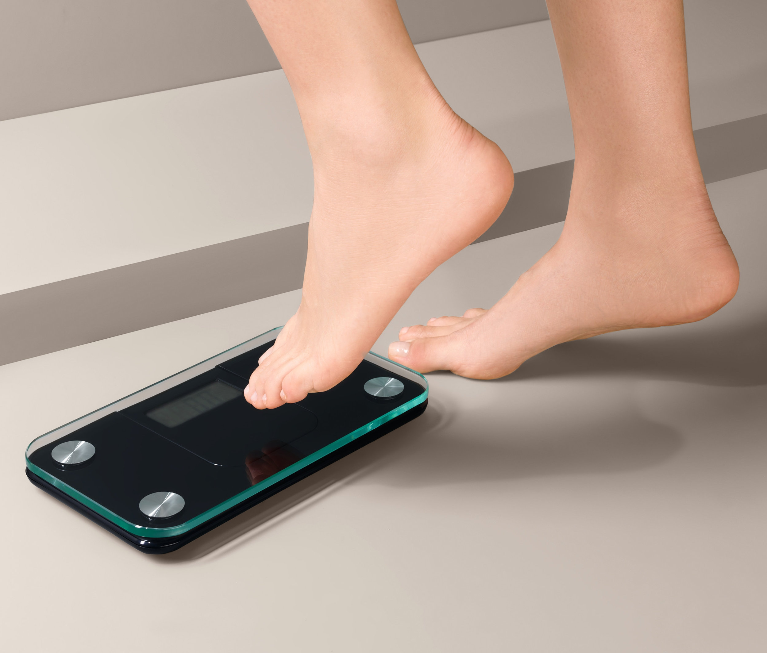 Stopa wchodzi na małą wagę łazienkową.