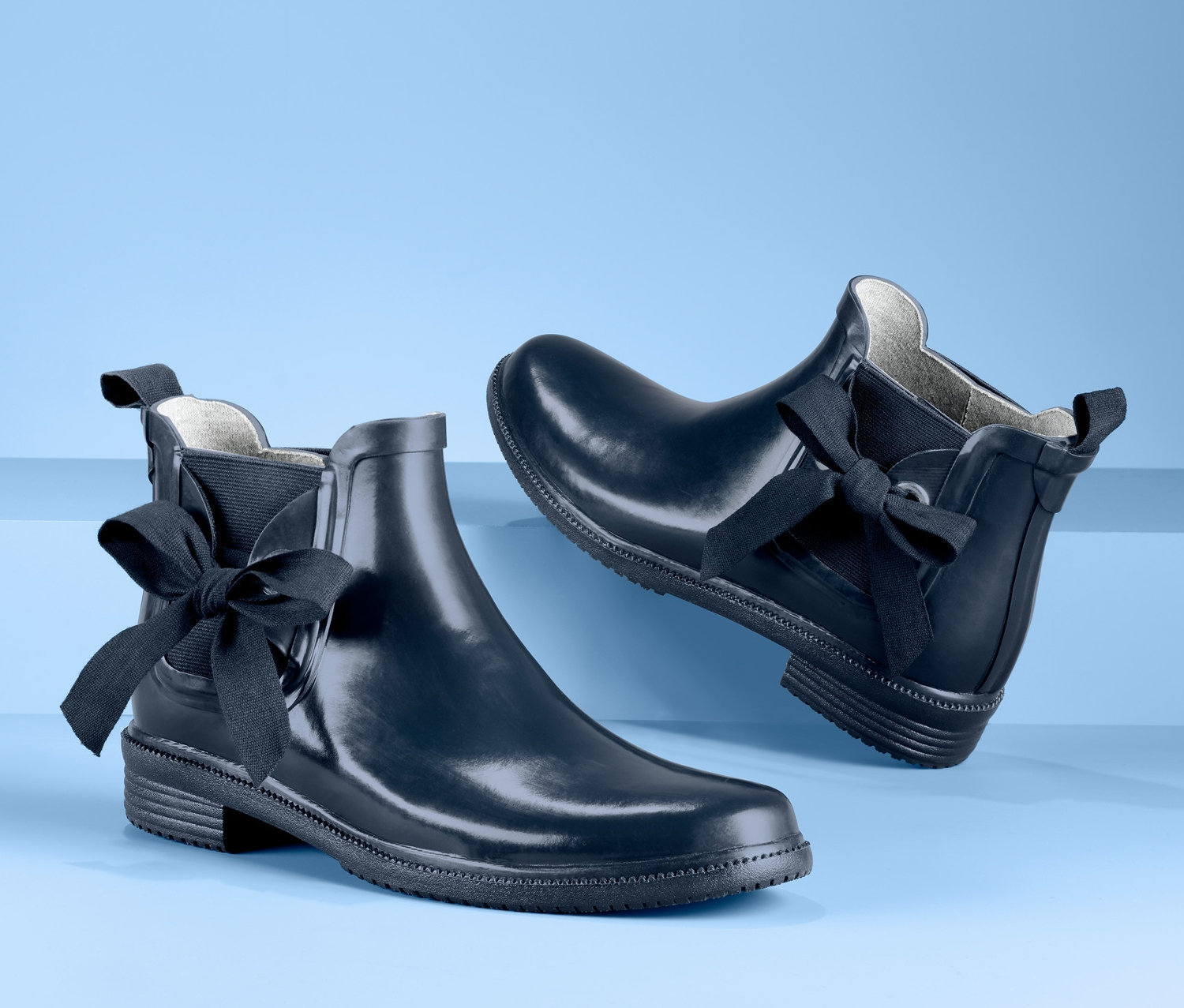 Dwa granatowe krótkie kalosze damskie z kokardkami.