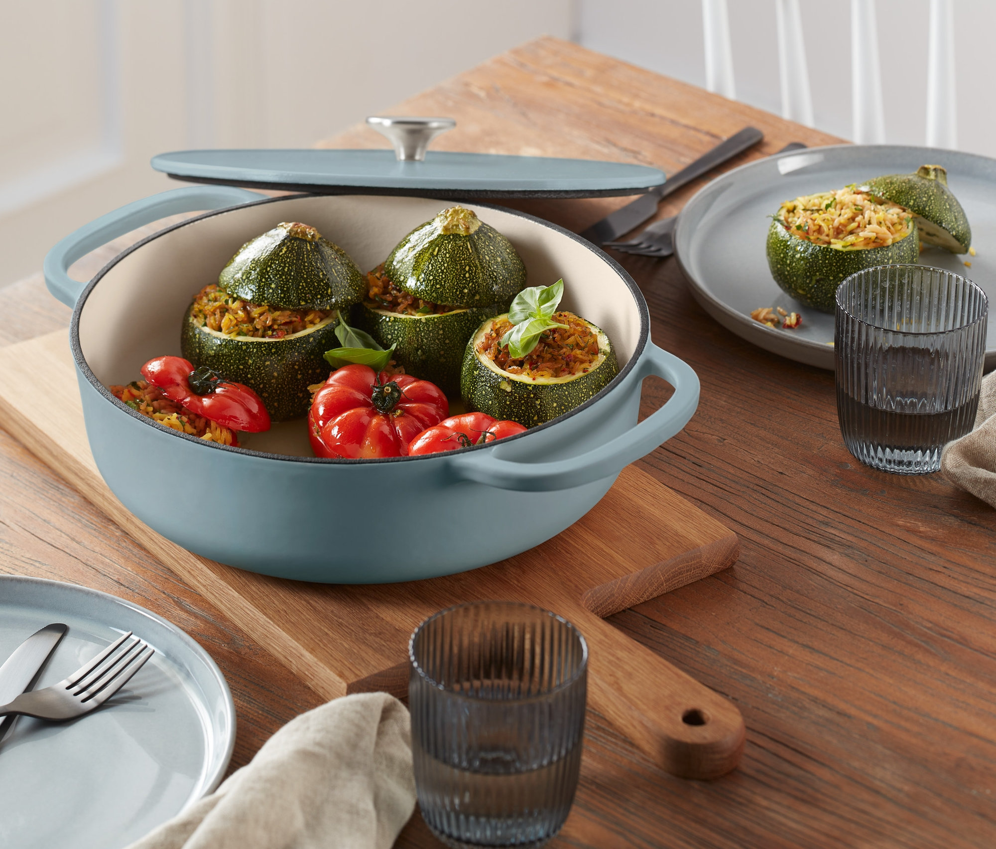 Niebieska żeliwna brytfanna z warzywami na drewnianym stole.
