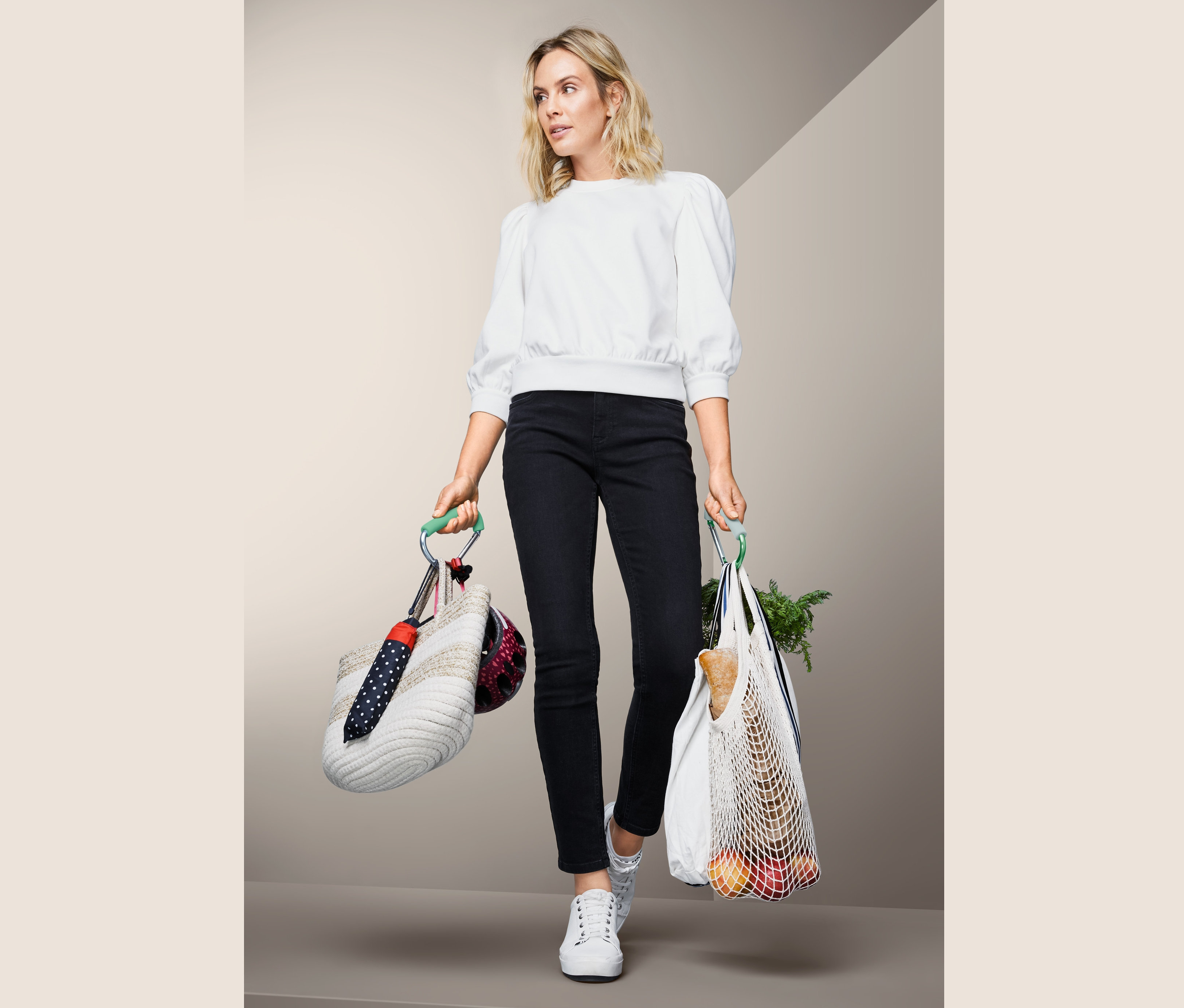 Kobieta trzyma torbę z kaskiem i parasolem przymocowanymi za pomocą 2 sztuk karabińczyków XXL oraz torbę na zakupy.