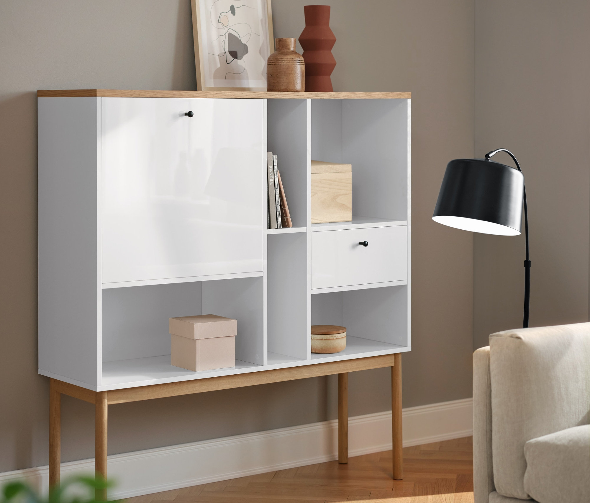 Biały sekretarzyk »Bekeson« i czarna metalowa lampa sufitowa w salonie.