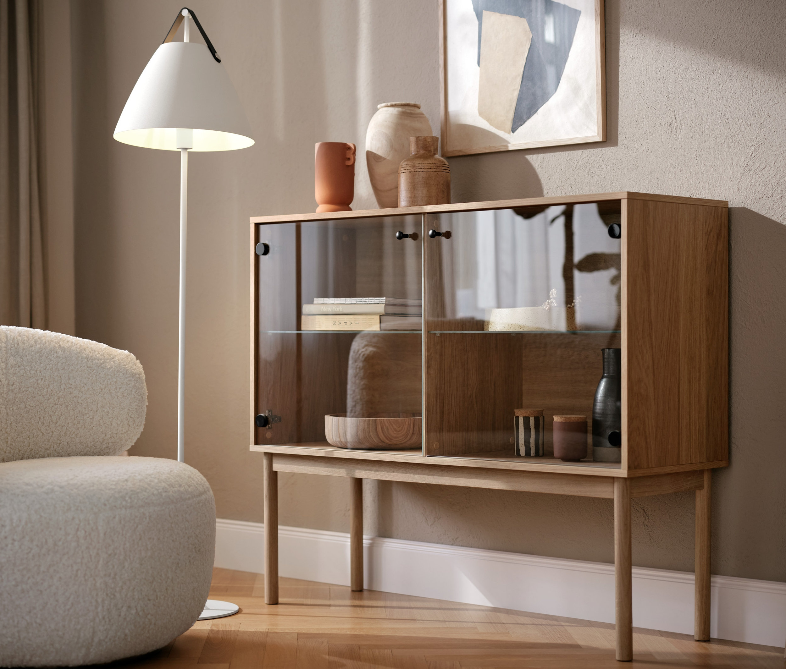 Fotel obrotowy i przeszklona szafka w salonie.