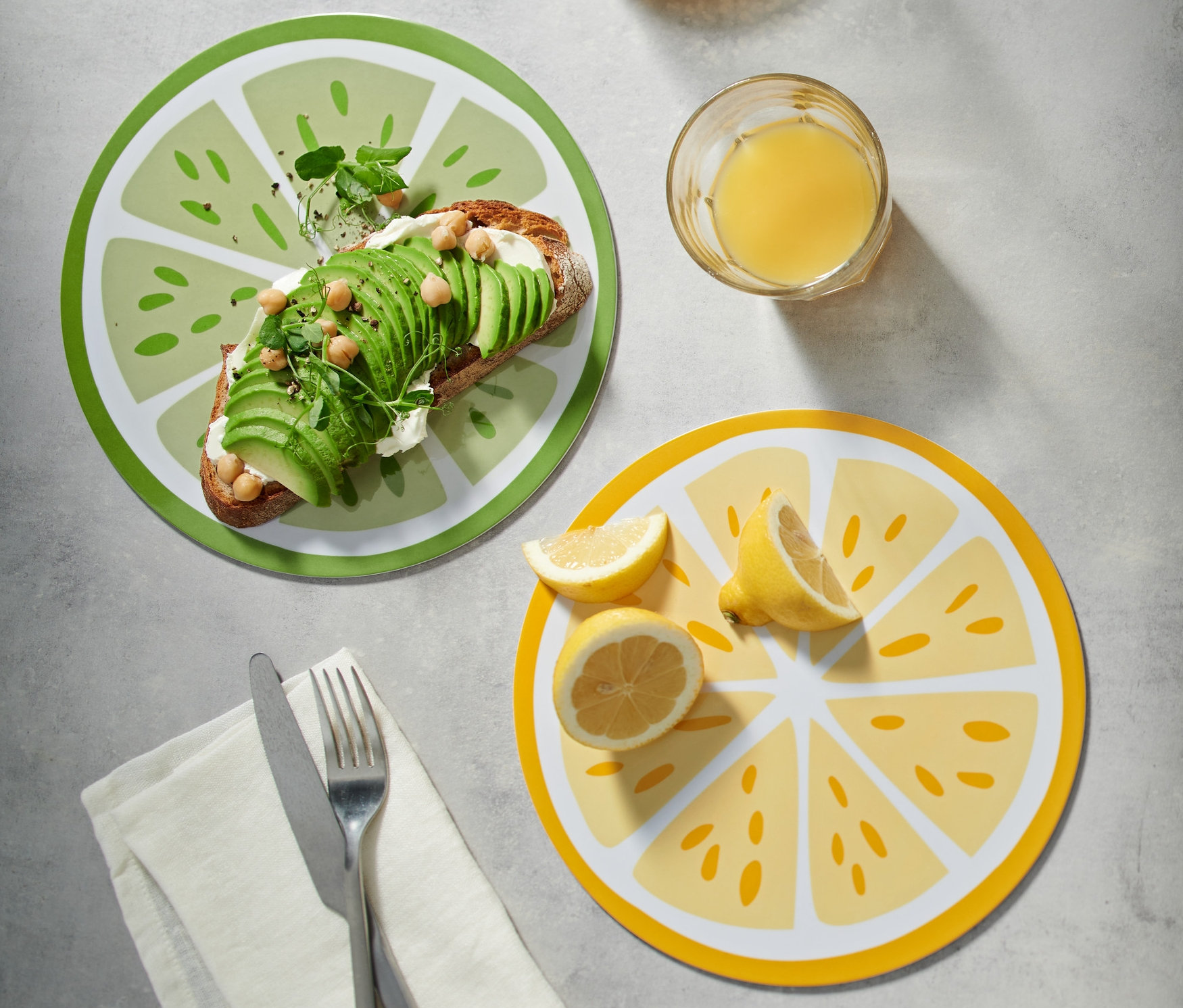 Tost z awokado na zielonej desce śniadaniowej. Obok dzbanek i szklanka soku. Deski śniadaniowe, 2 sztuki.