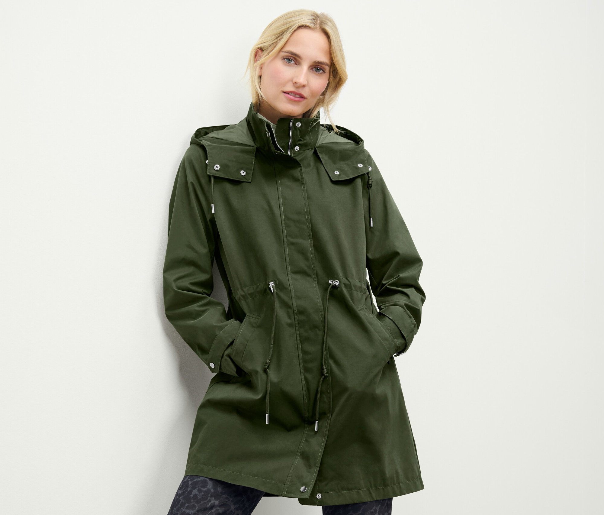 Kobieta ma na sobie zieloną parkę z kapturem.