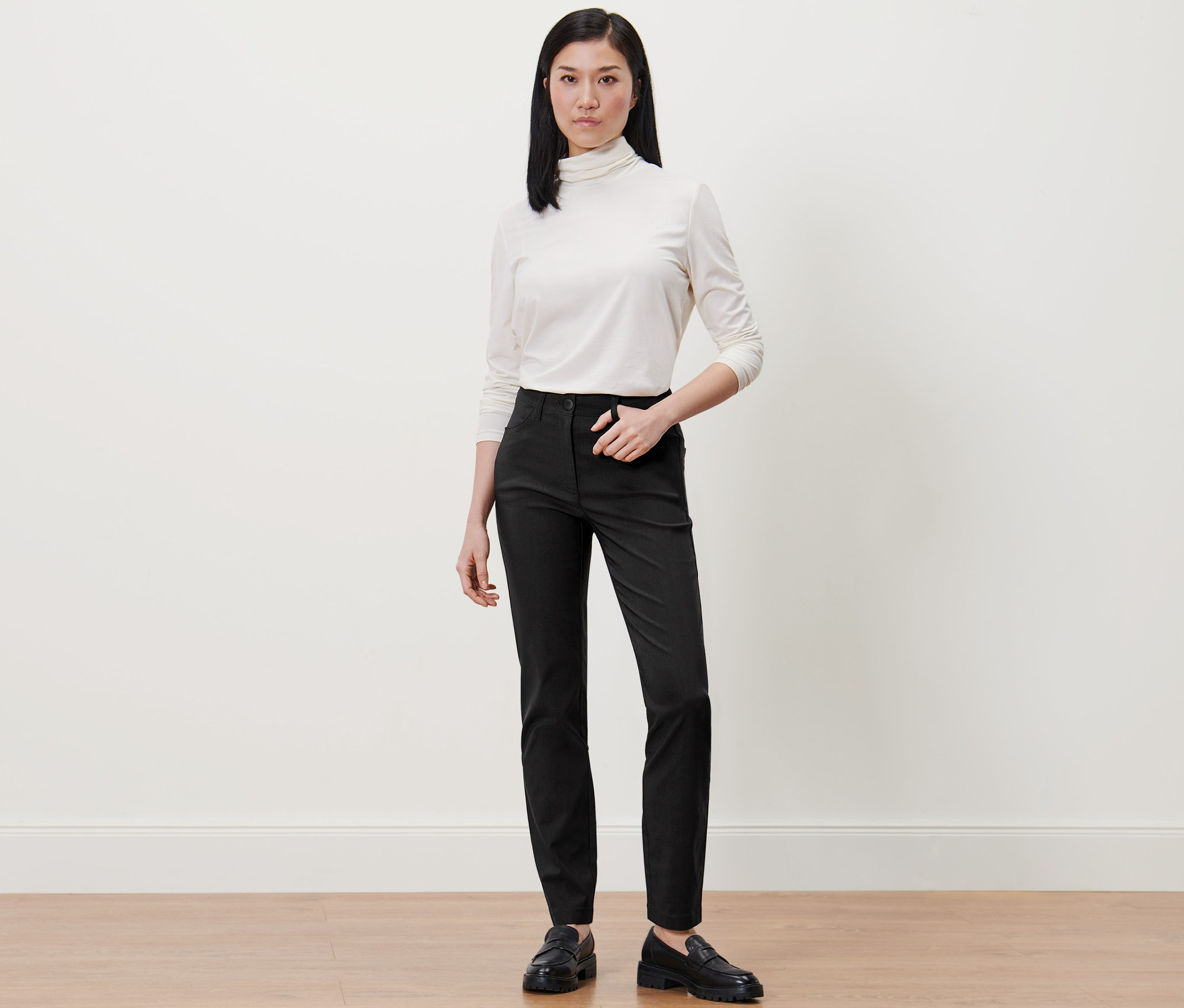 Kobieta w białym golfie i czarnych spodniach z bengaliny.