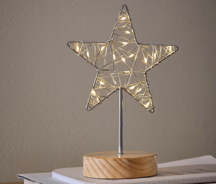 Ozdobna figurka LED „Gwiazda” stoi na książkach na szafce.