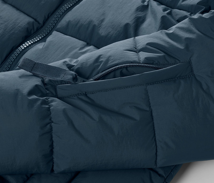 Szczegółowy widok granatowej, pikowanej kurtki narciarskiej z zamkiem błyskawicznym i kieszenią.