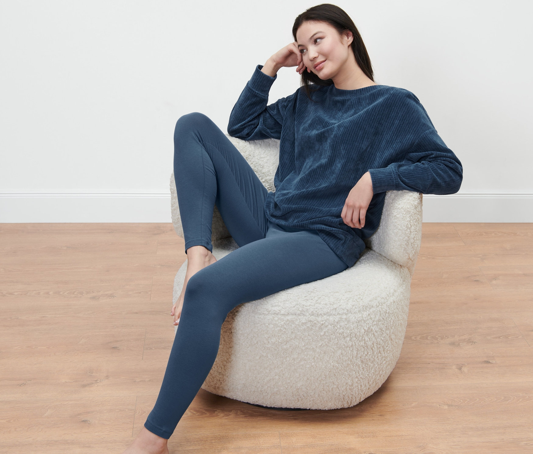 Kobieta siedzi w fotelu i ma na sobie piżamę z legginsami.