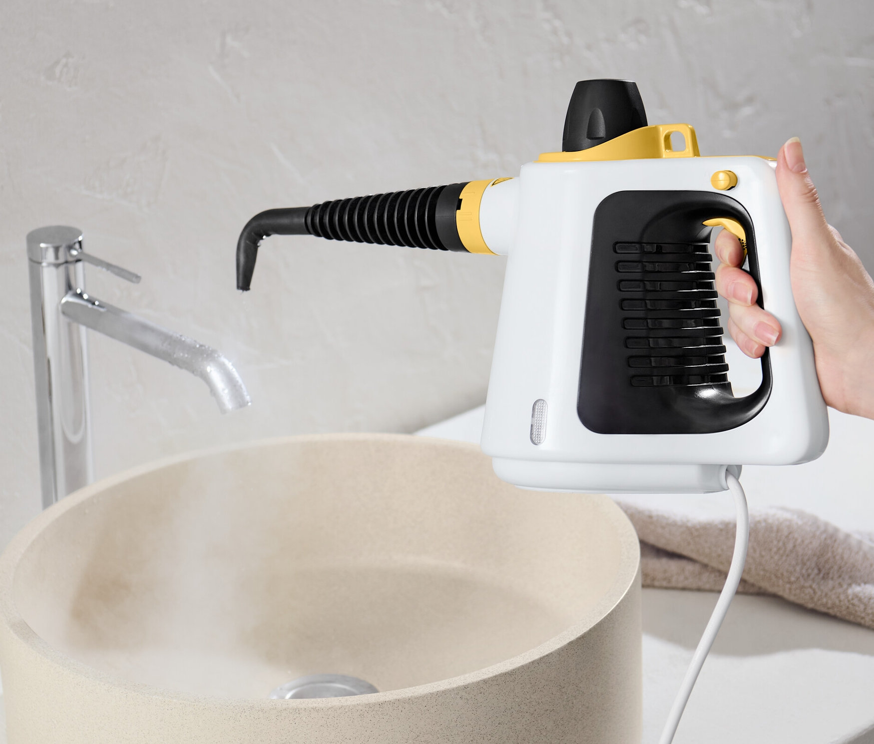 Ręka trzyma myjkę parową nad umywalką.