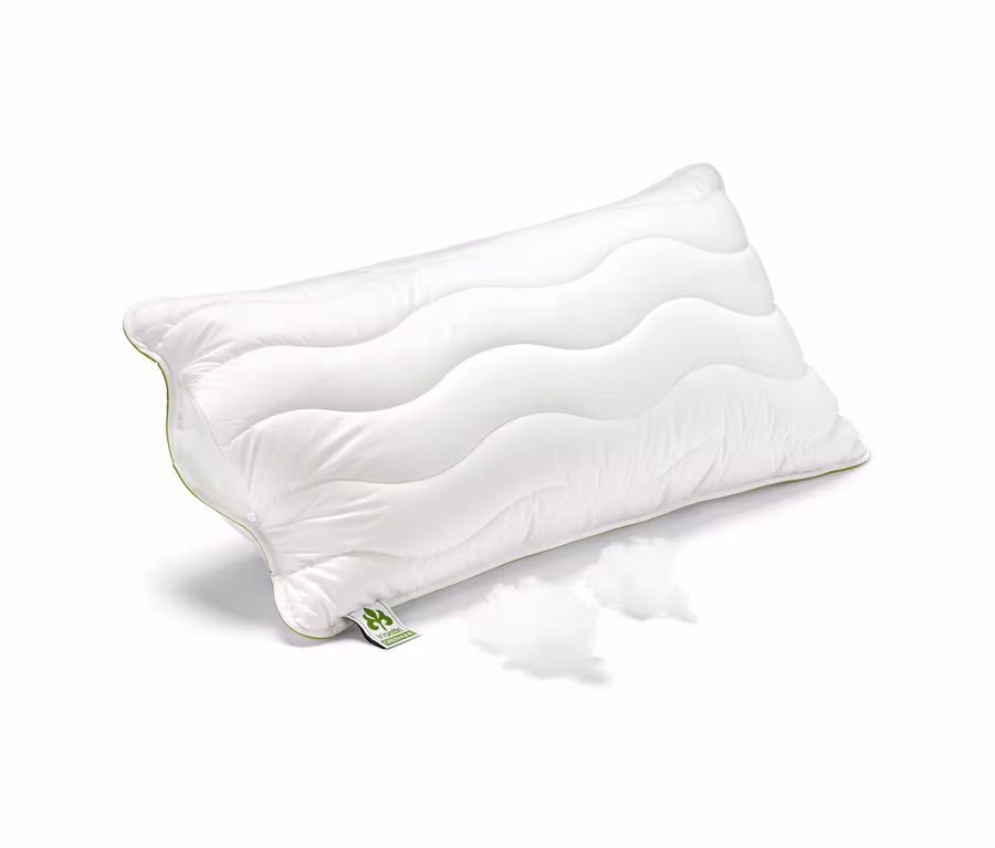 Biała poduszka irisette® greenline Megafil® BIO, ok. 65 x 100 cm, leży na białym tle obok dwóch kępek wypełnienia.