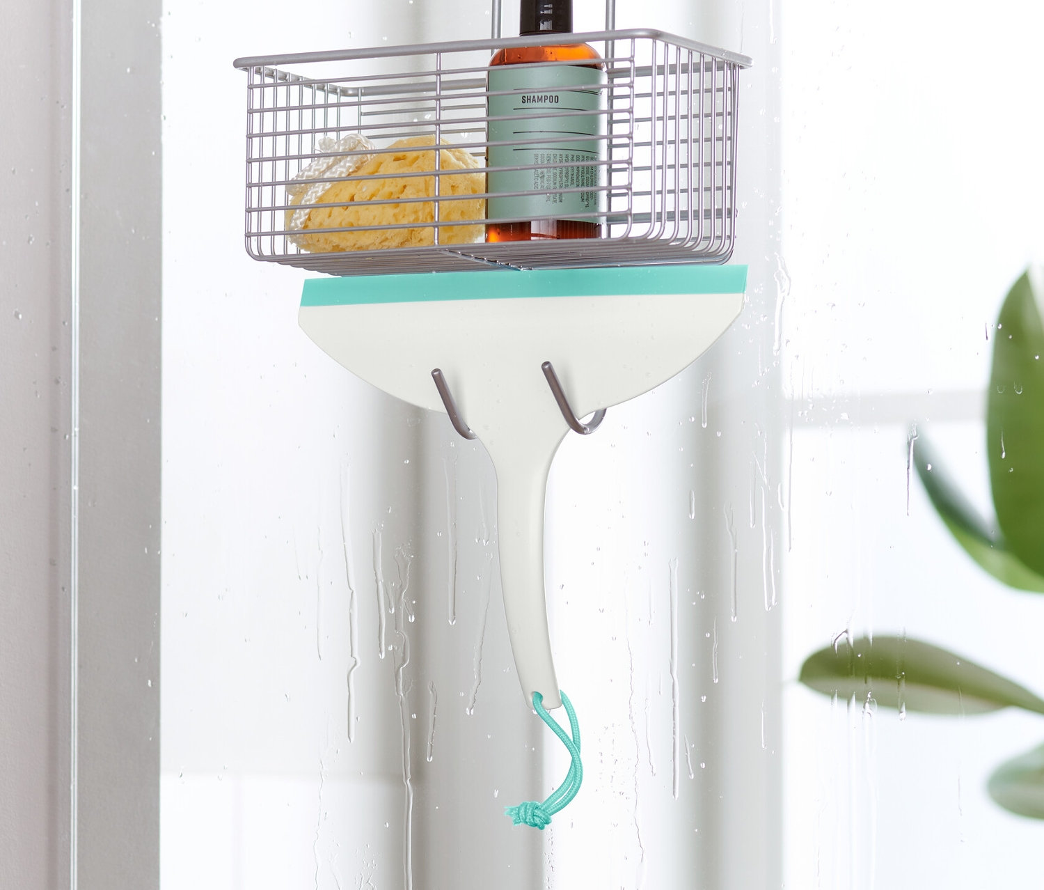 Ściągaczka do wody wisi na drzwiach kabiny prysznicowej.