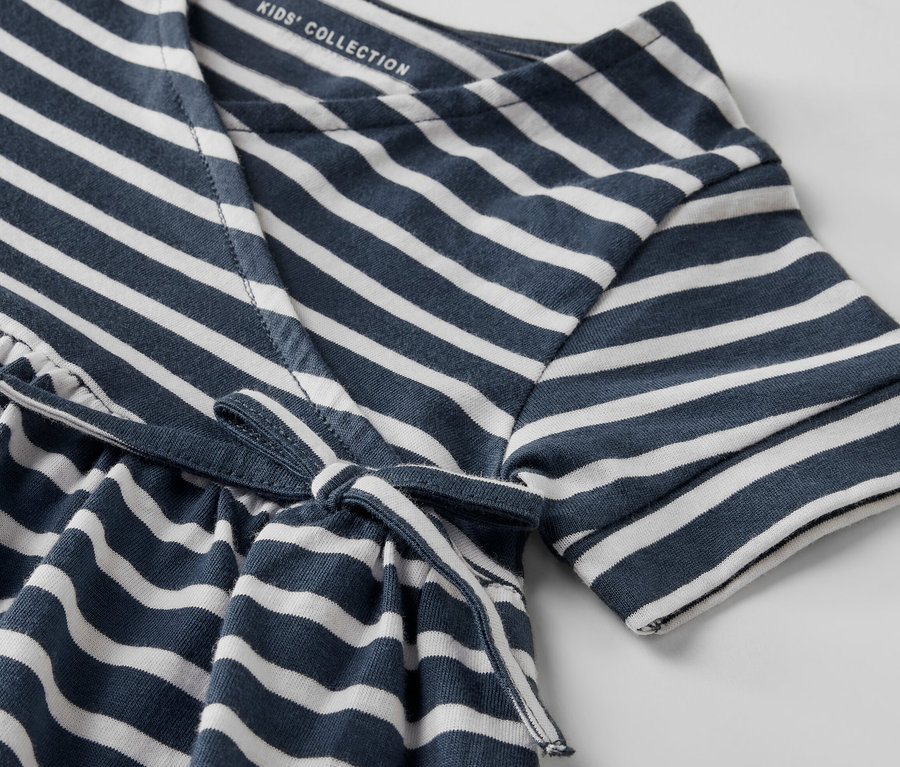 Zbliżenie na sukienkę dżersejową w niebiesko-białe paski, wiązaną w pasie.