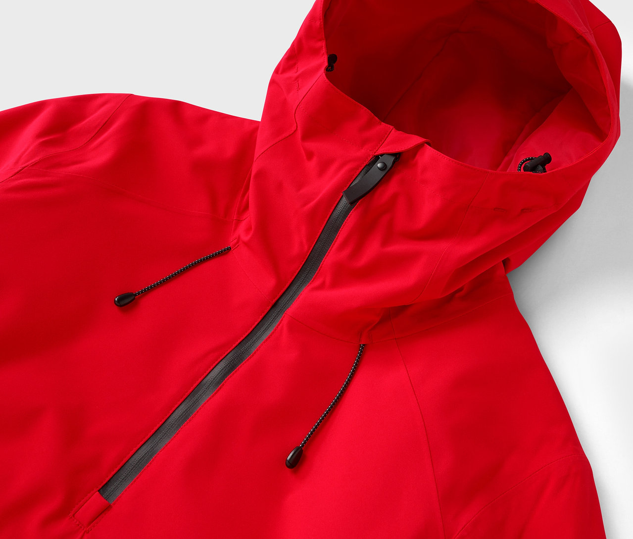 Zbliżenie na czerwoną kurtkę z kapturem i czarnym zamkiem błyskawicznym.