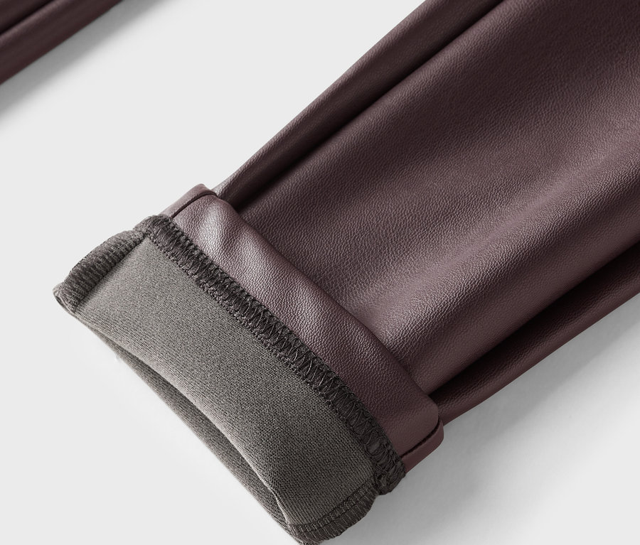 Zbliżenie brązowych skórzanych spodni z podwiniętym brzegiem i szarą podszewką.