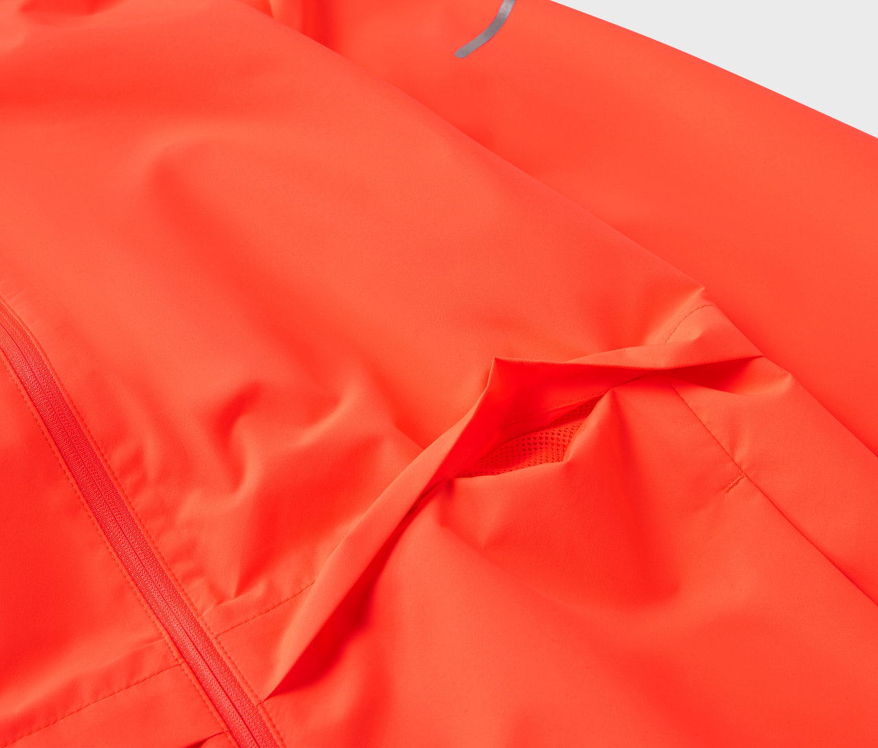 Szczegół neonowo pomarańczowej kurtki z kieszenią i odblaskowym paskiem na rękawie.