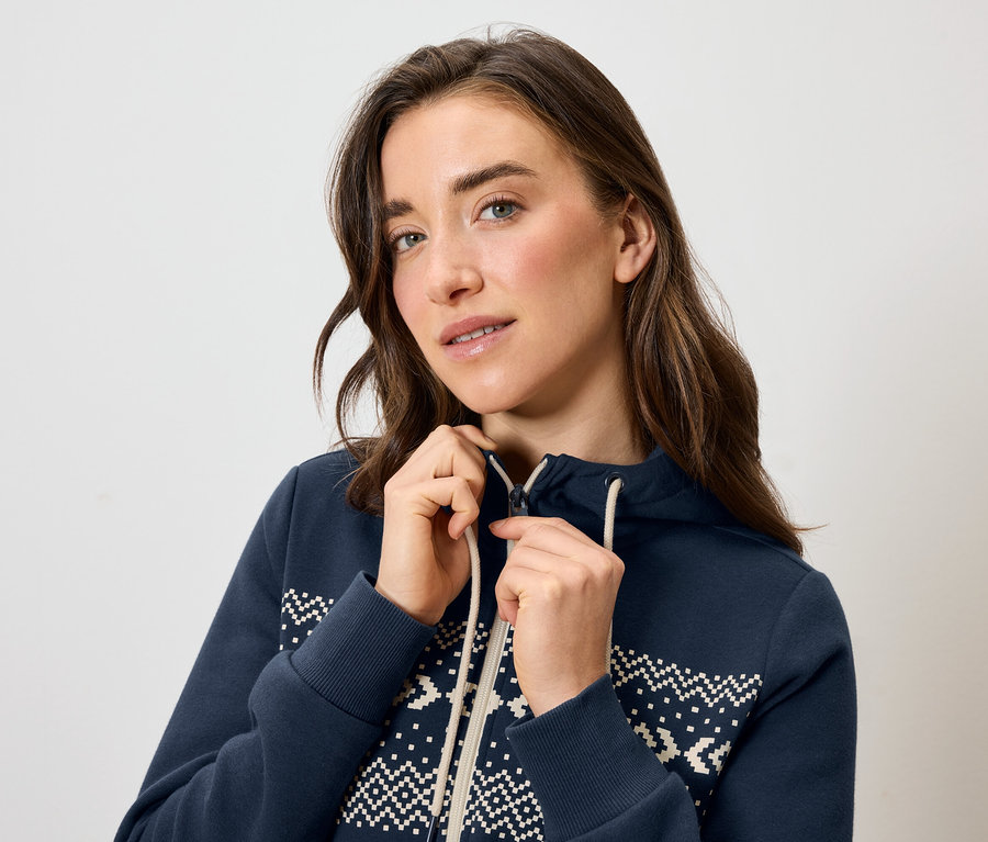 Kobieta zapina niebieską bluzę z kapturem i białym wzorem.