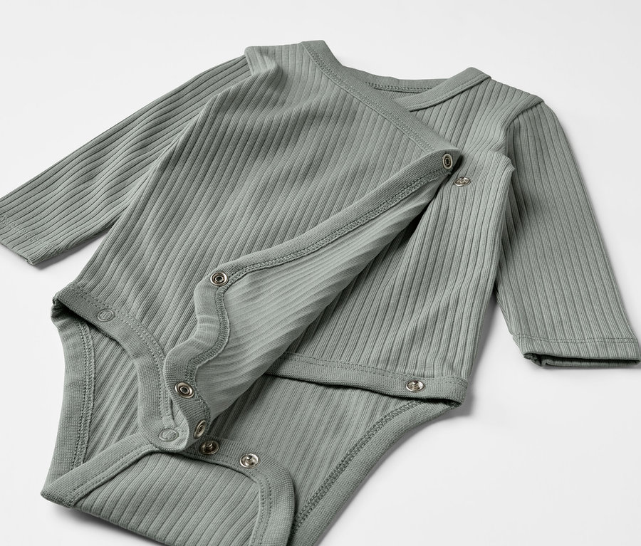 Dwa szarozielone body z długim rękawem dla niemowląt leżą na sobie.