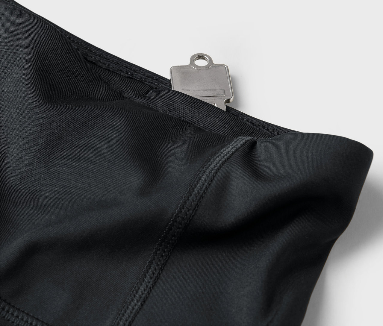 Zbliżenie czarnych legginsów z kluczem w kieszeni.