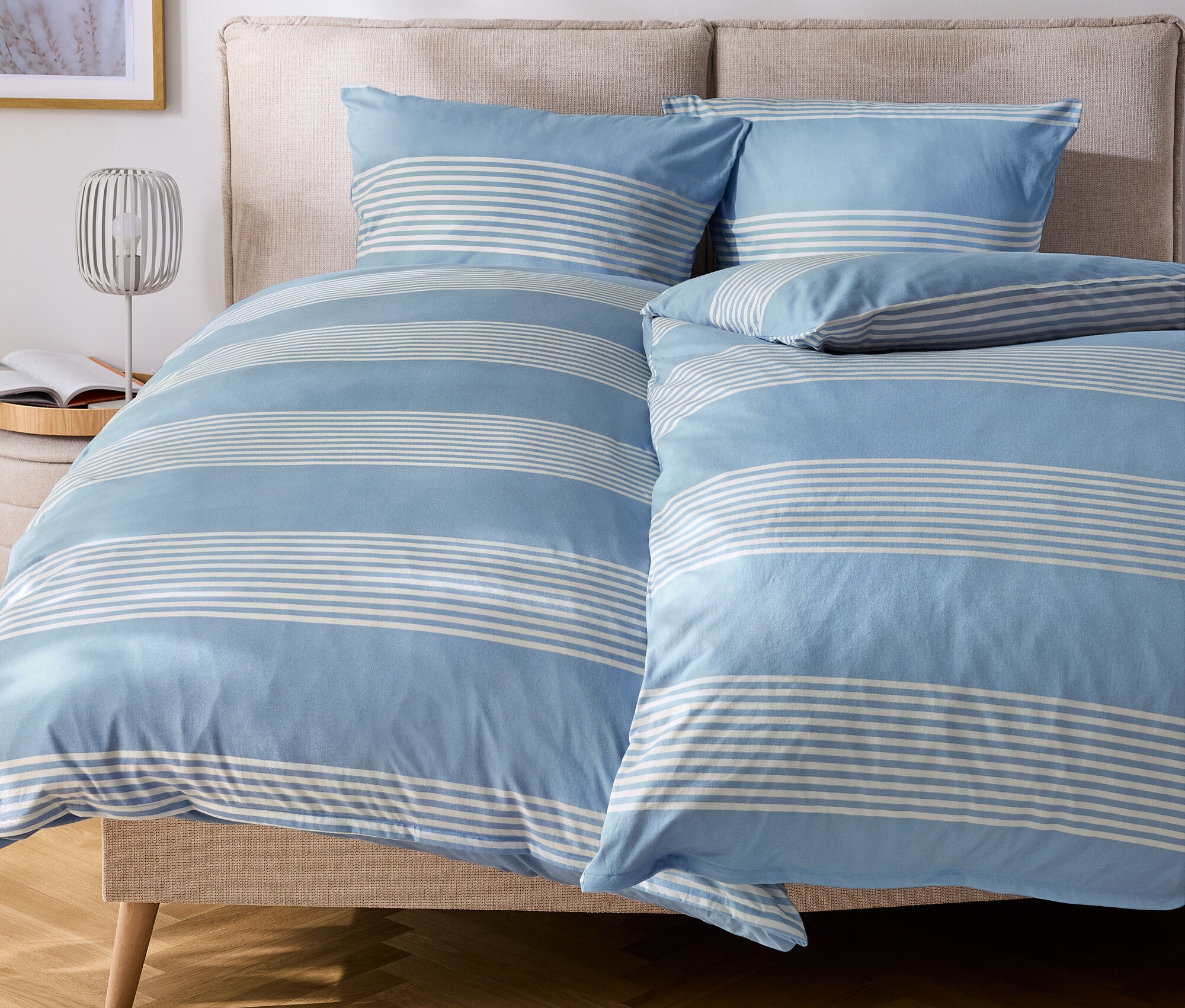 Łóżko z niebiesko-białą pościelą w paski i poduszkami.