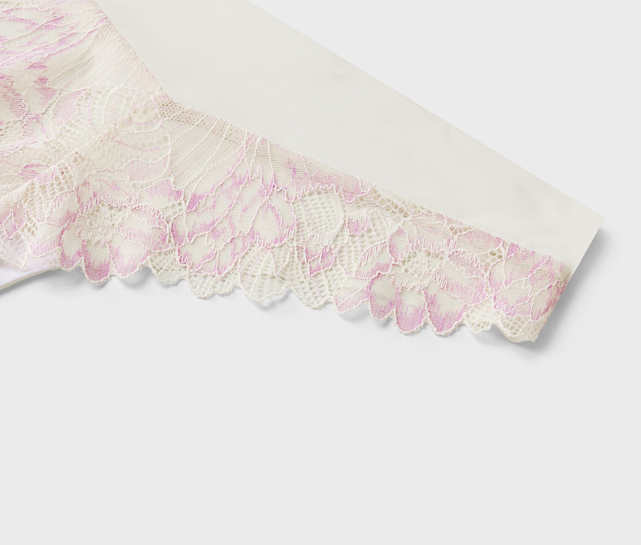 Szczegółowy widok białej tkaniny z różową koronką w kwiatowy wzór na rękawie.