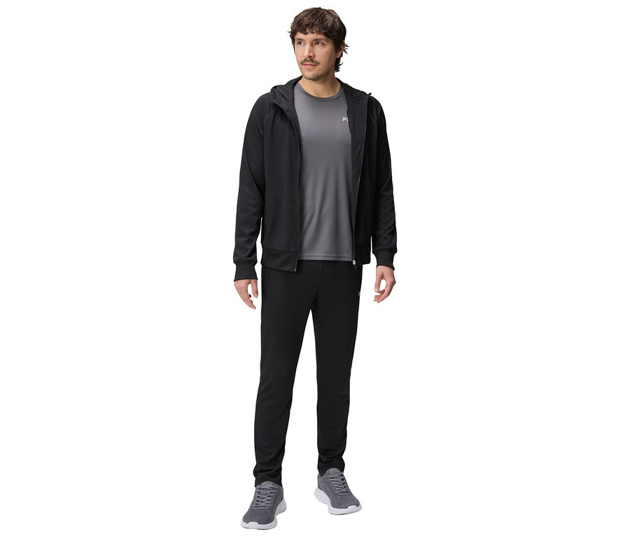 Mężczyzna w czarnej bluzie z kapturem, szarym T-shircie i czarnych spodniach dresowych oraz szarych butach sportowych.