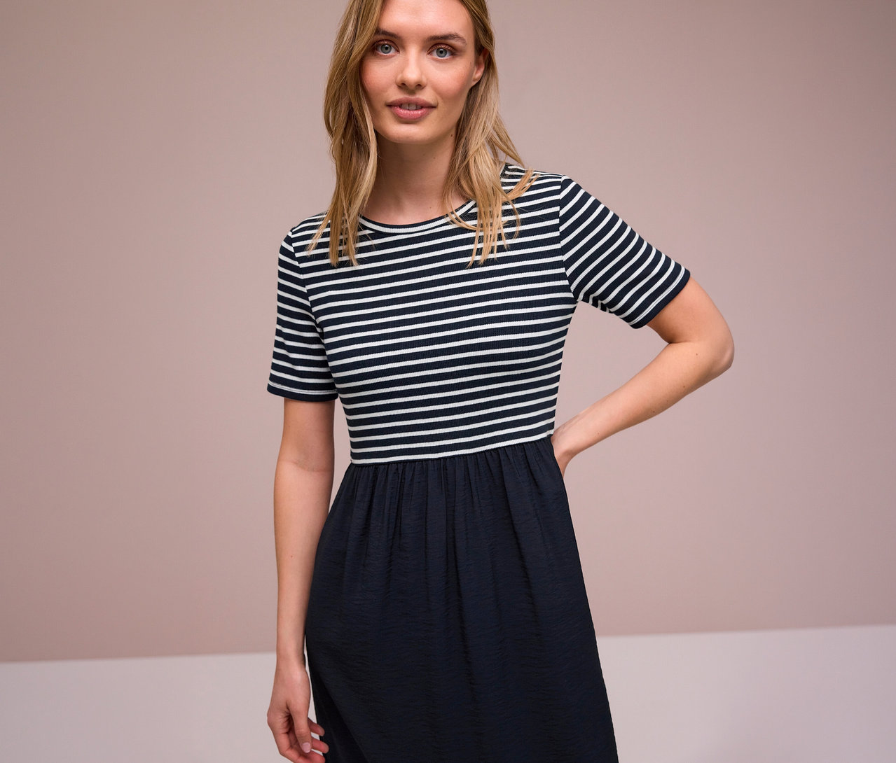 Kobieta w sukience Street One w paski z krótkim rękawem i ciemną spódnicą.