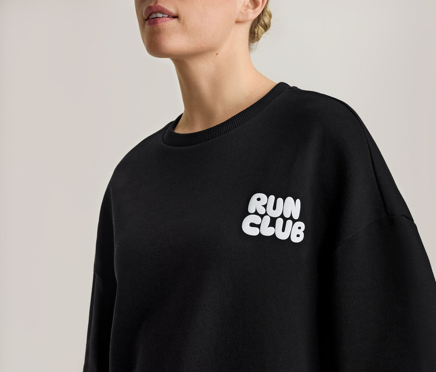 Kobieta w czarnej bluzie z białym napisem "RUN CLUB".