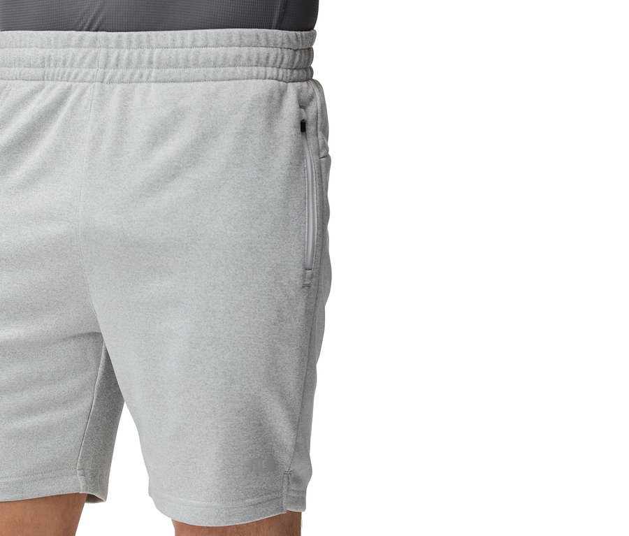 Zbliżenie na jasnoszare szorty treningowe z zamkiem błyskawicznym przy kieszeni.