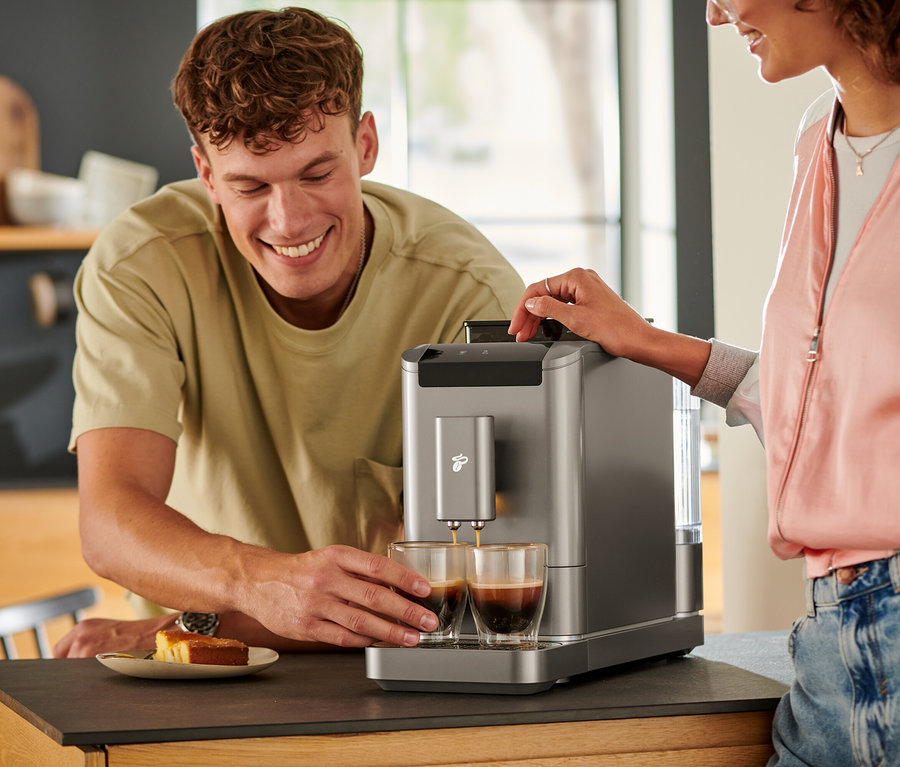 Mężczyzna patrzy, jak kawa wlewa się do dwóch szklanek z automatycznego ekspresu do kawy »Esperto2 Caffè« w kolorze titanium silver.
