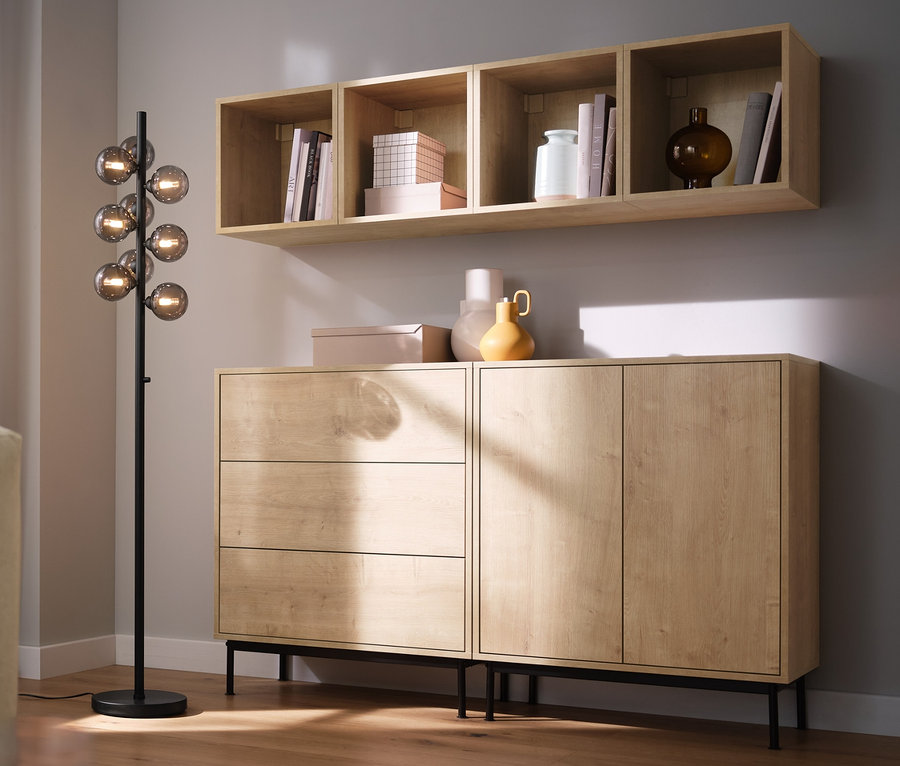 Pokój dzienny z sofą, lampą stojącą »Szklane kule« i modułami regału »Flemming« w dekorze dębowym.