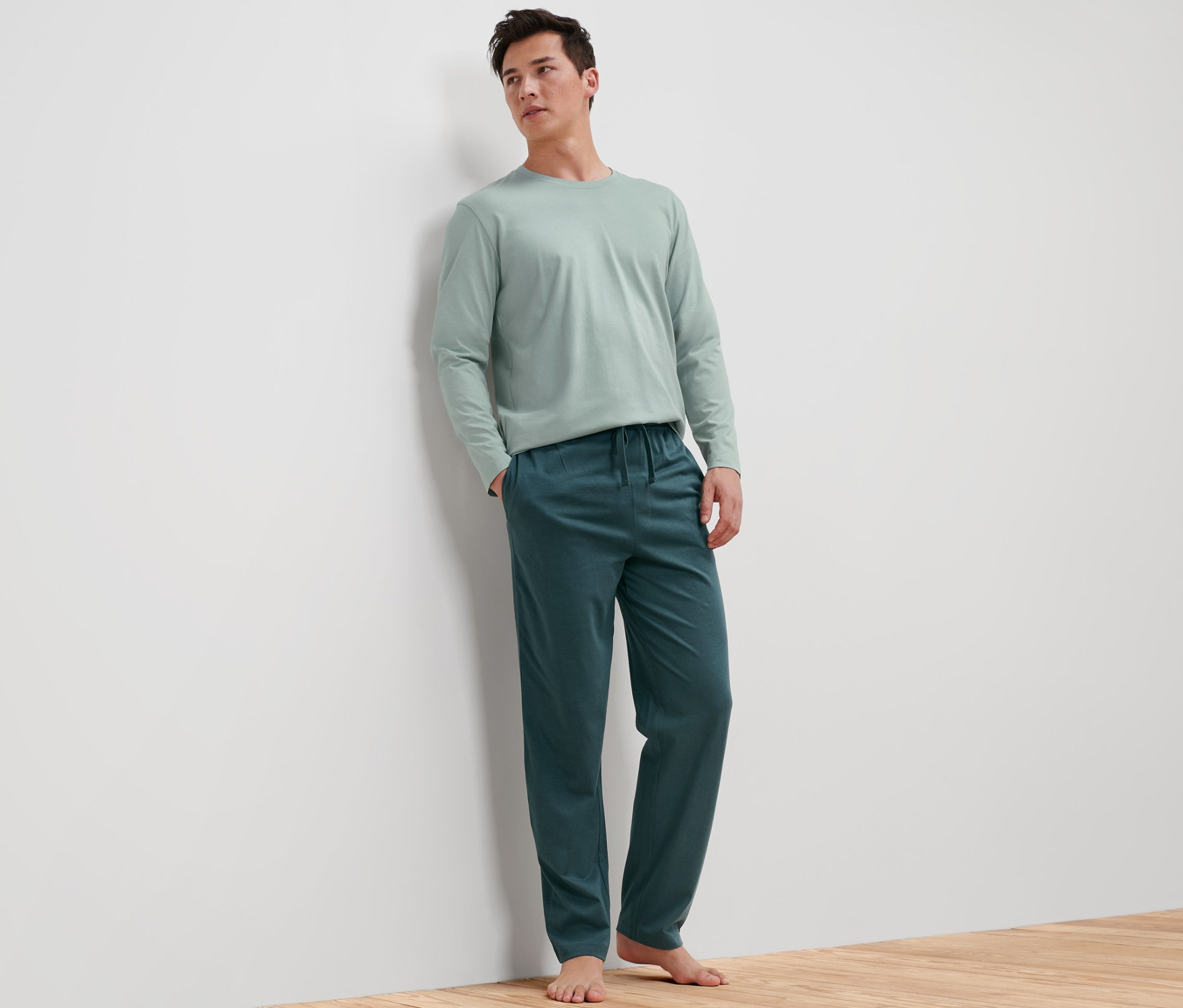 Mężczyzna oparty o ścianę w piżamie męskiej.