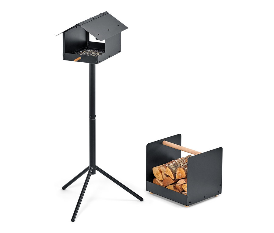 Czarny karmnik dla ptaków na stojaku i uchwyt na drewno z polanami.