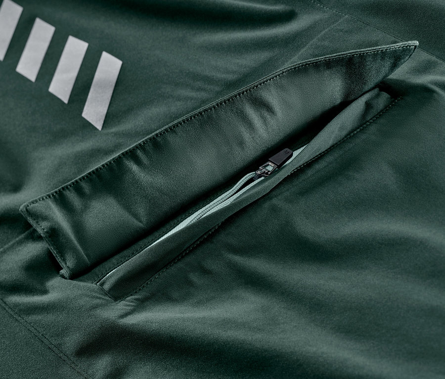 Szczegół rowerowej kurtki przeciwdeszczowej ze srebrnymi paskami i kieszenią na zamek błyskawiczny.