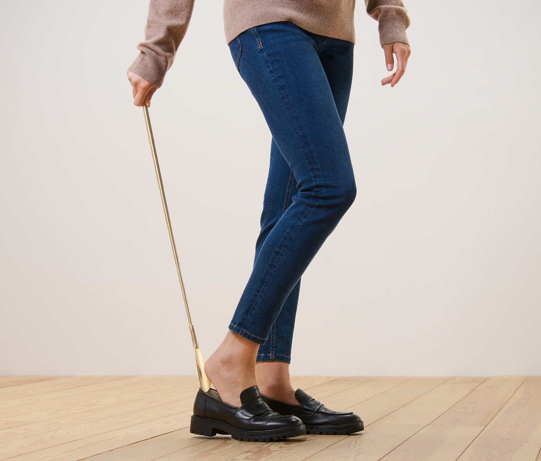 Osoba używa teleskopowej łyżki do butów, aby założyć czarne buty.