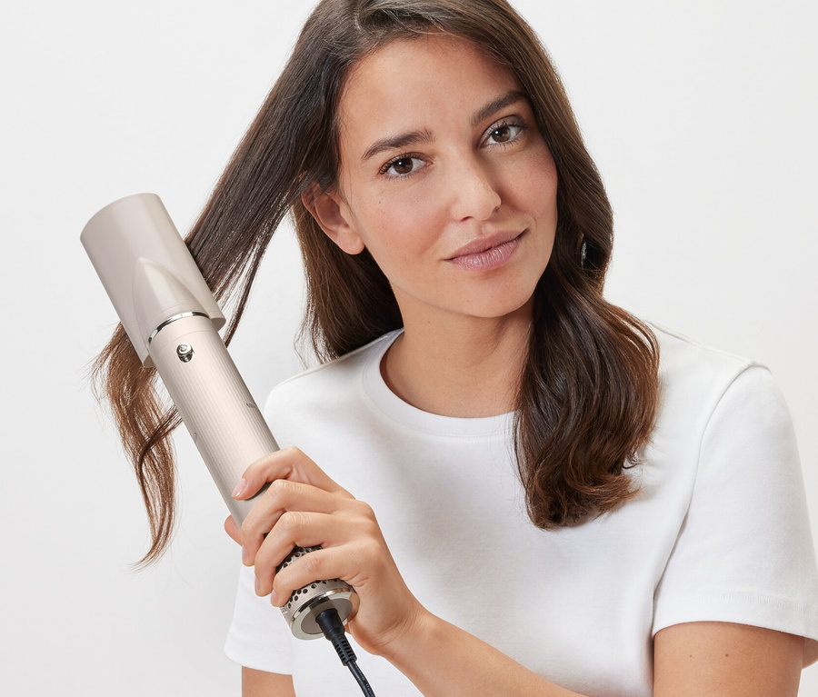Kobieta stylizuje włosy suszarko-lokówką 5 w 1.