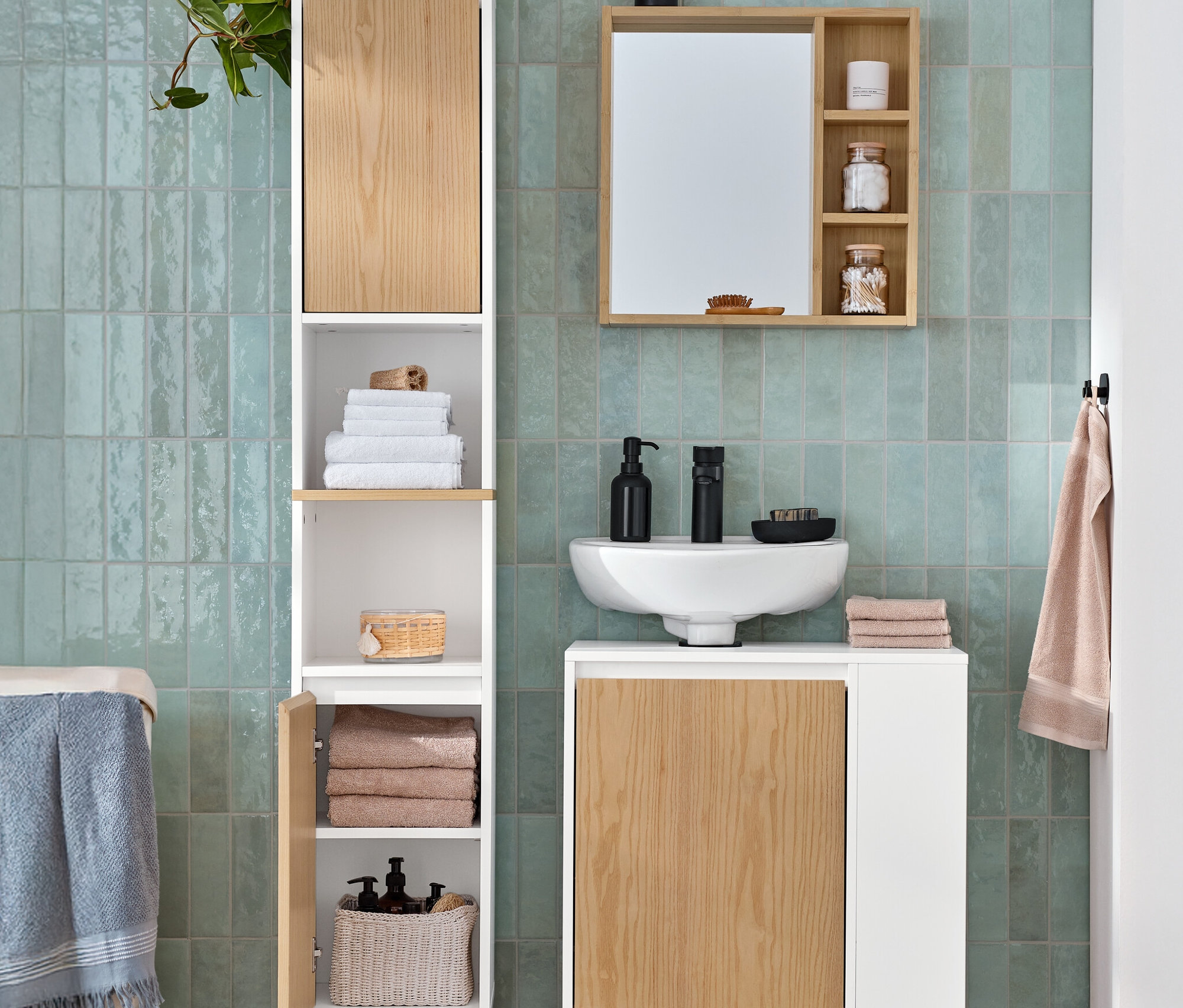 Łazienka wyposażona jest w wysoką szafkę łazienkową, szafkę pod umywalkę z boczną przegródką i lustro z półkami.