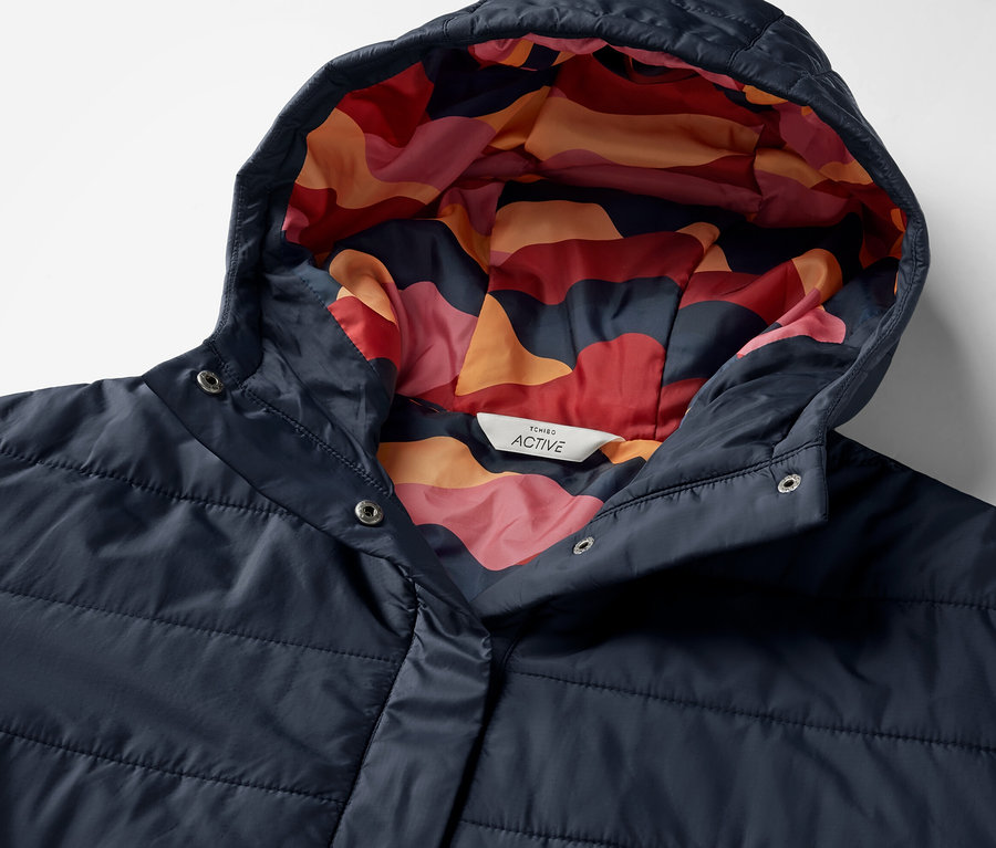 Szczegół granatowego poncho outdoorowego z kapturem i kolorowym wzorem wewnątrz.