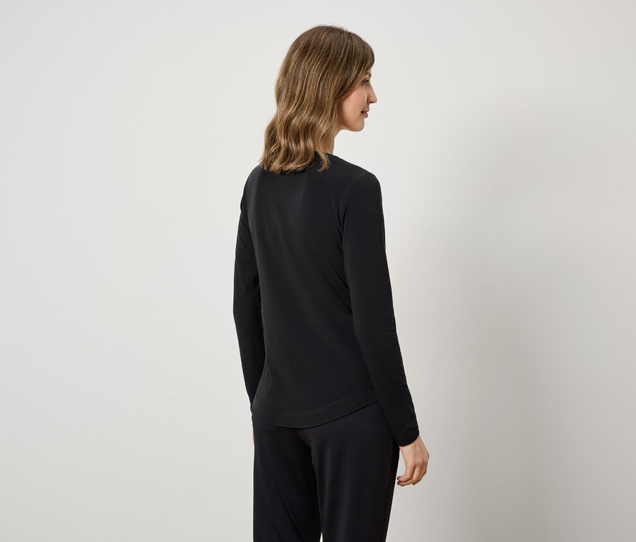 Kobieta z tyłu ma na sobie czarną bluzkę z długim rękawem i czarne spodnie.